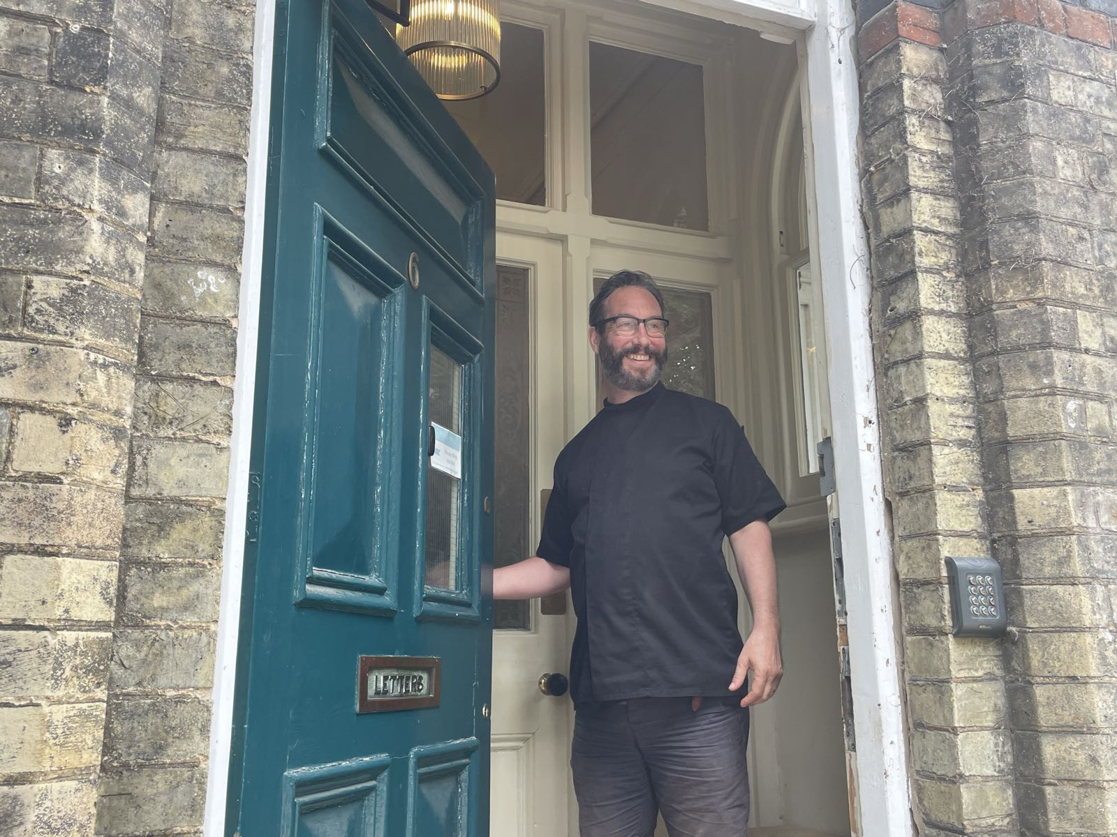 A member of the Floatwell team holding open the front door of the villa in Cambridge