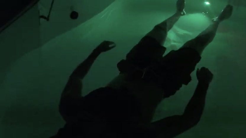 A floater held up by the dense Epsom-salt water in a dimly lit pod