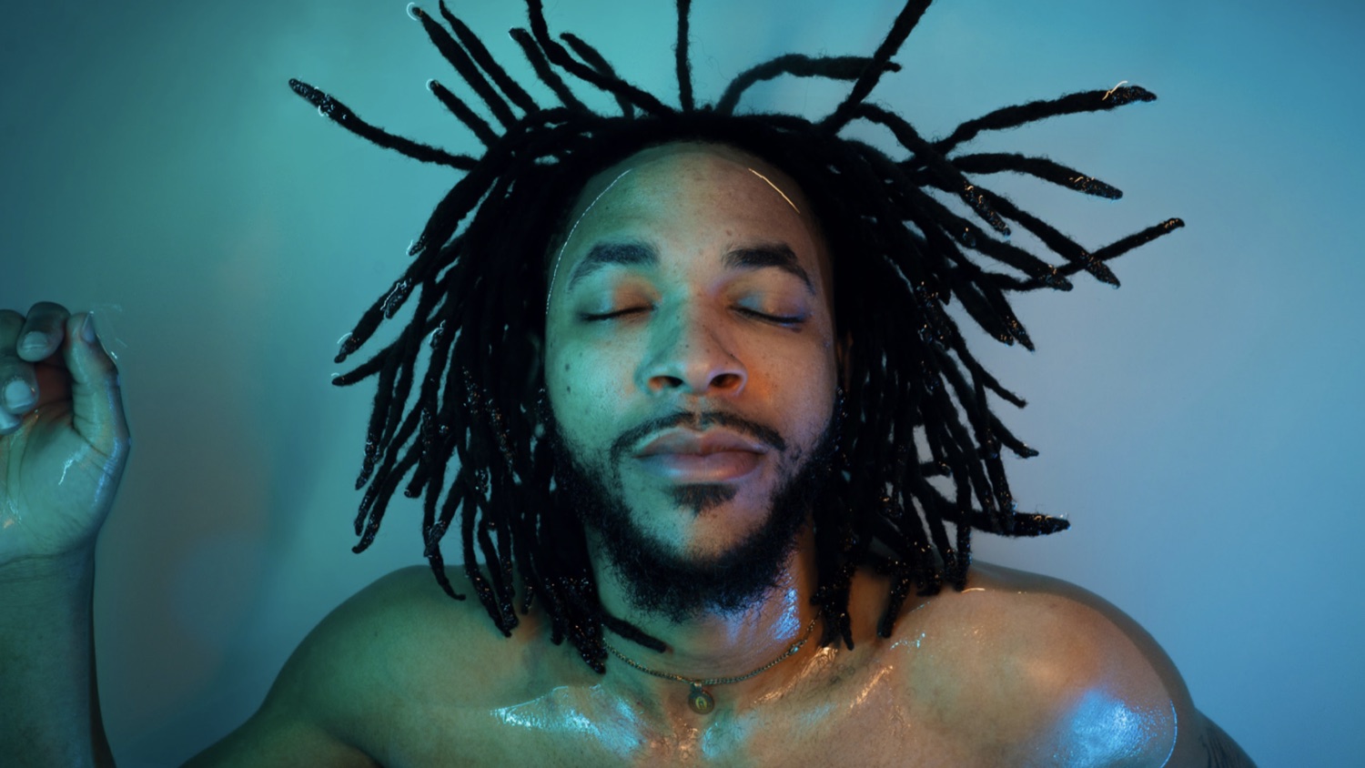 A floater with eyes closed in cool blue light, water beading on the skin