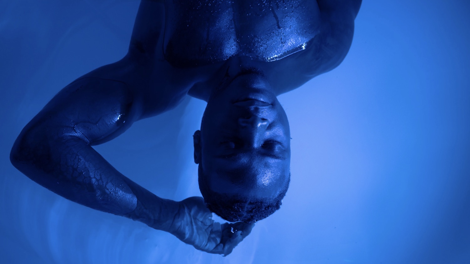 A floater at rest in deep blue light, eyes closed