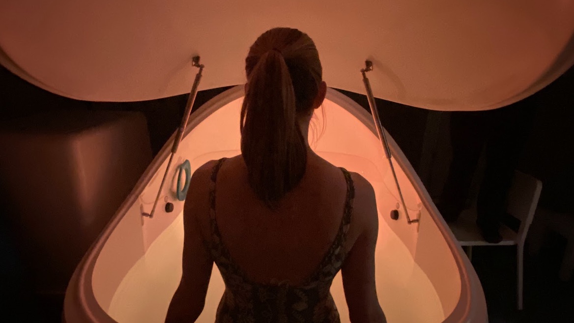 A floater stepping into a warmly lit pod