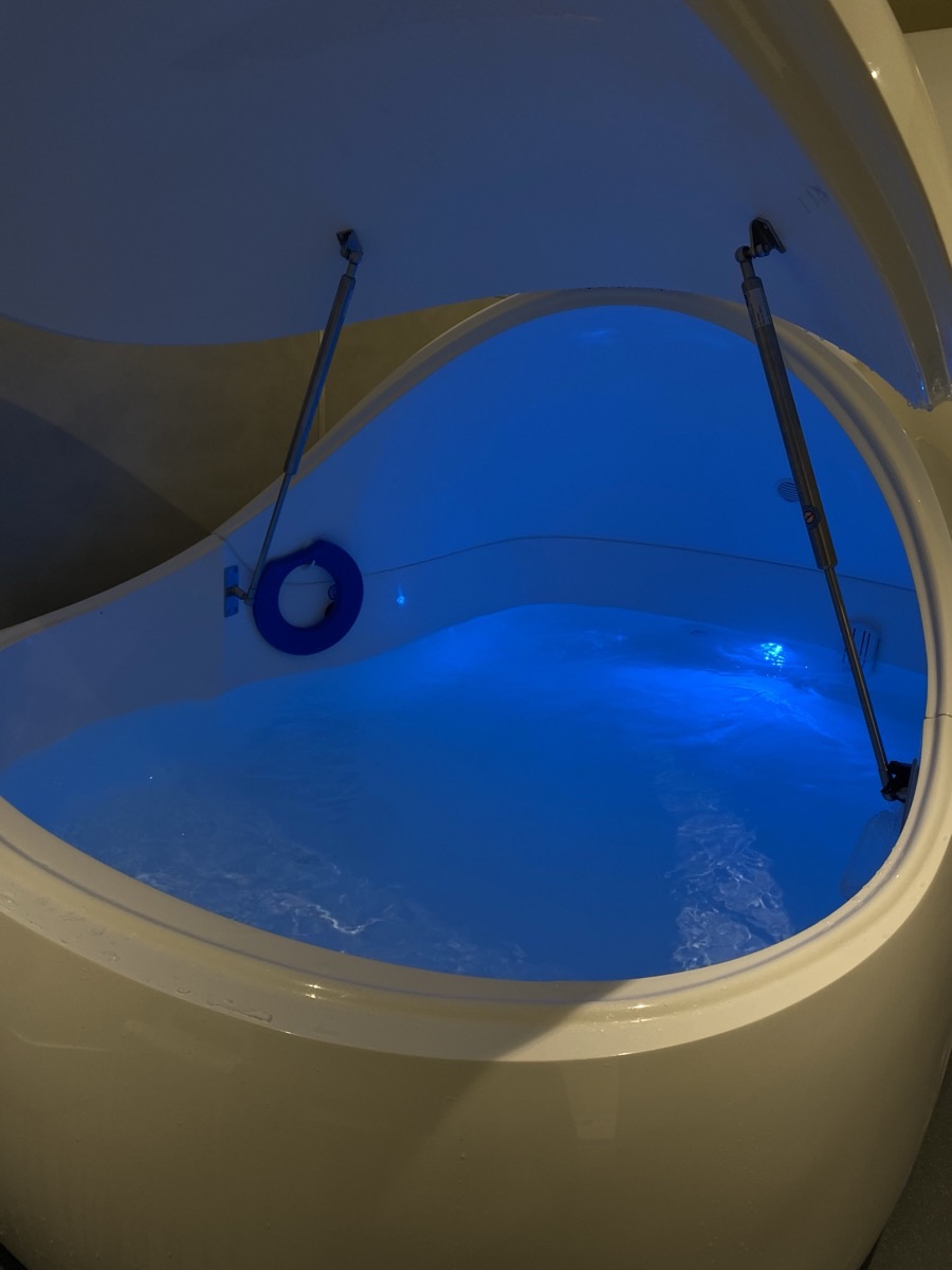 The open floatation pod, lit blue, at Floatwell Cambridge