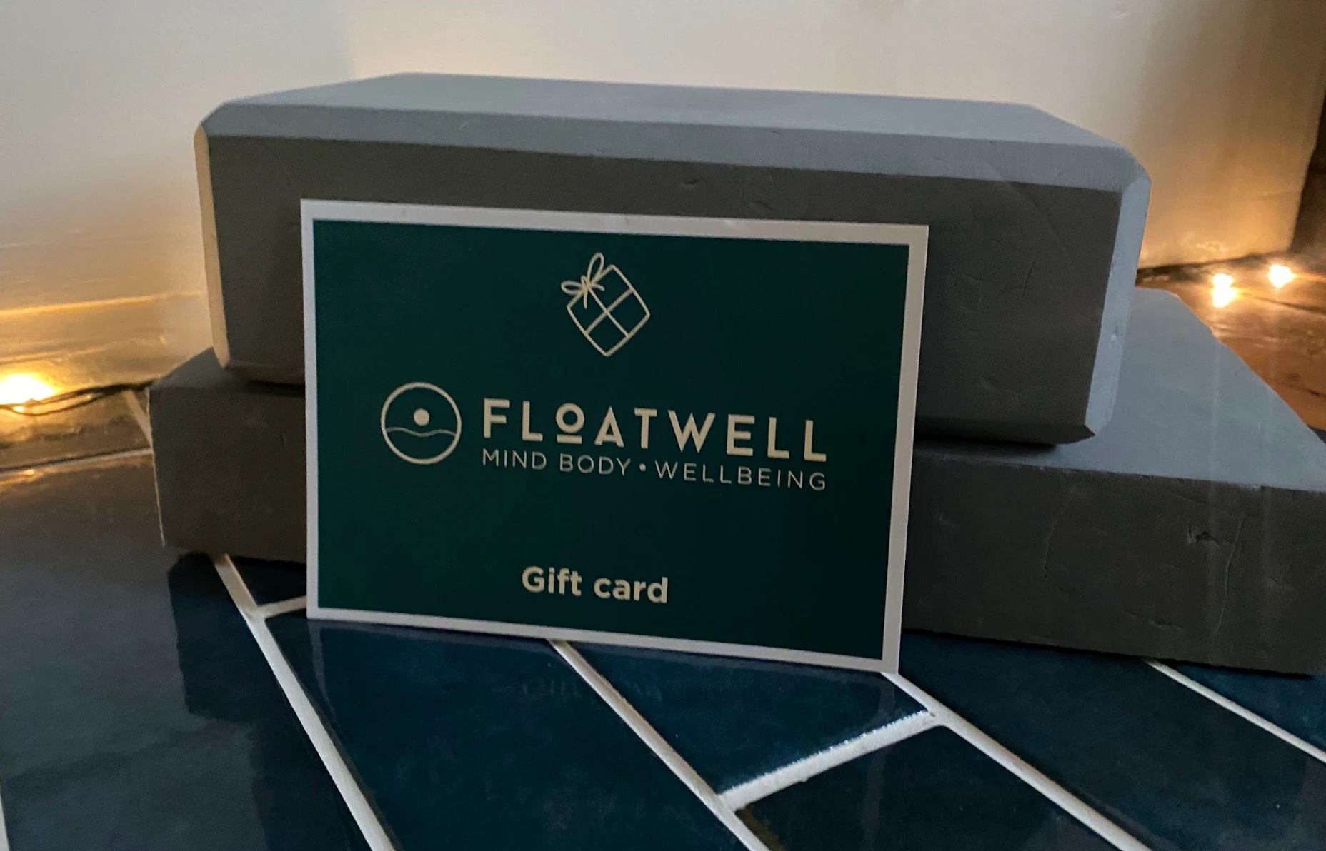 A Floatwell gift card resting against yoga blocks at the Floatwell villa