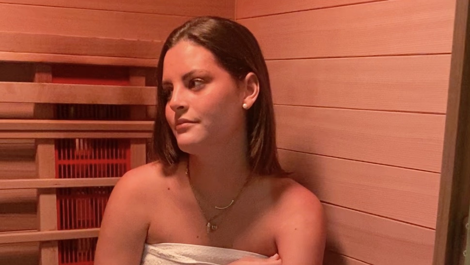A guest wrapped in a towel in the warm-lit infrared sauna