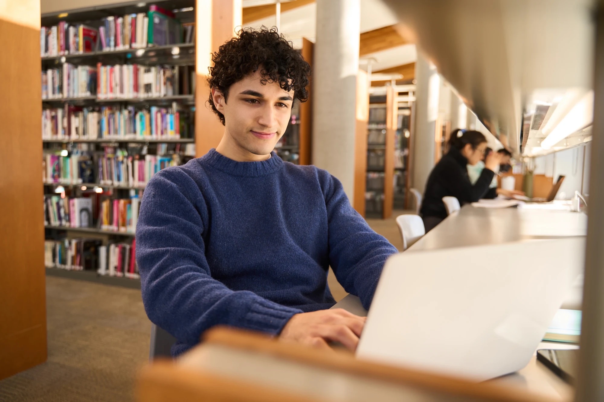 A student working on a laptop at a library desk