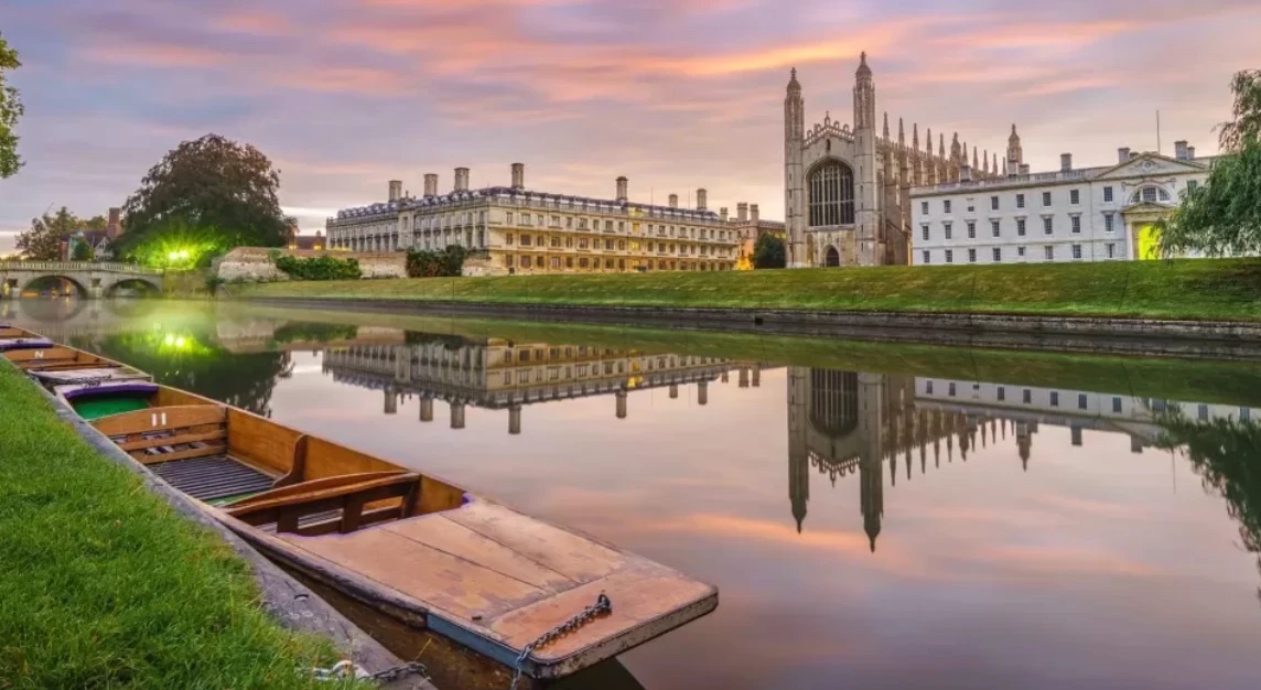 King's College Chapel reflected in the River Cam at dusk, with punts moored along the bank